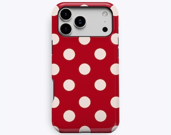 Puede incluir: Una funda para smartphone de color rojo con un patrón repetitivo de lunares blancos. La funda tiene un recorte rectangular en la parte superior para un sistema de triple cámara y un flash. La palabra KUKA está impresa en letras pequeñas en la parte inferior central.