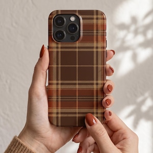 Puede incluir: Una funda para smartphone con un patr&oacute;n de cuadros en tonos marr&oacute;n, beige y naranja oscuro. El dise&ntilde;o consiste en l&iacute;neas horizontales y verticales que se cruzan formando una cuadr&iacute;cula de tart&aacute;n cl&aacute;sica en toda la parte trasera.