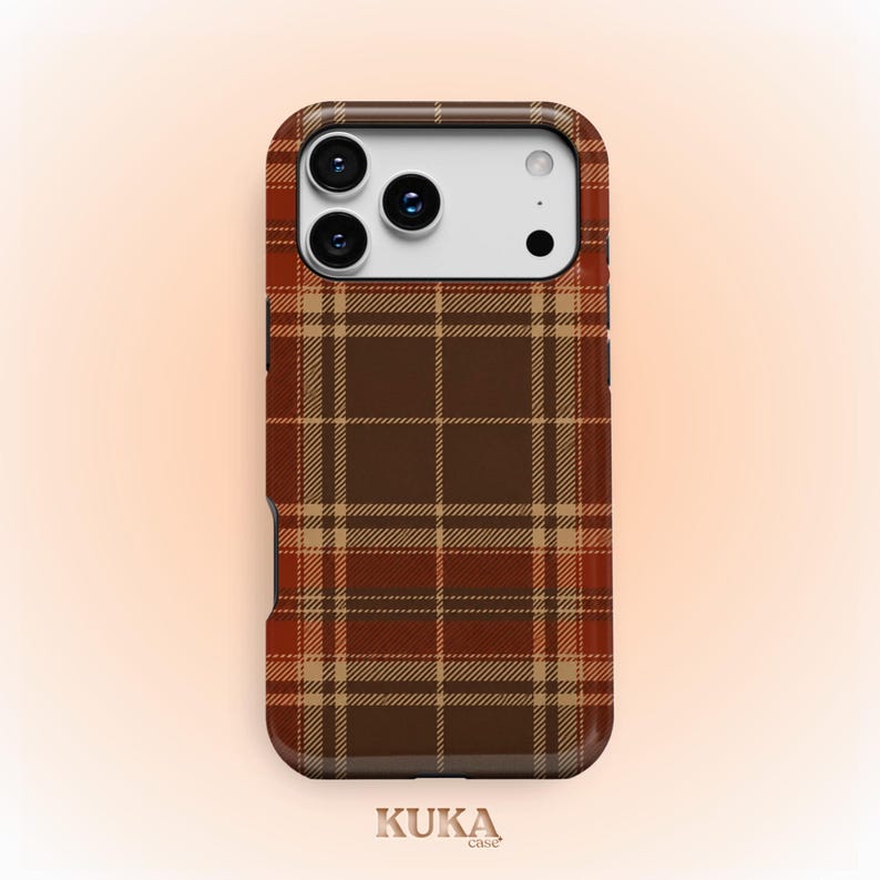 Puede incluir: Una funda para smartphone con un patr&oacute;n de cuadros en tonos marr&oacute;n, beige y naranja. La funda tiene un recorte rectangular para un sistema de triple c&aacute;mara y un flash. El texto KUKA case aparece impreso en letra peque&ntilde;a al pie.