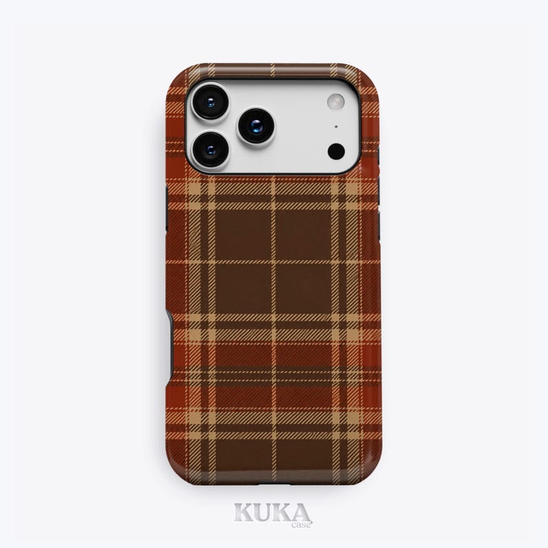 Puede incluir: Una funda para smartphone con un patr&oacute;n de cuadros en marr&oacute;n, beige y naranja oscuro. La funda tiene un recorte rectangular en la parte superior para un sistema de triple c&aacute;mara y flash. La palabra KUKA est&aacute; impresa en letras peque&ntilde;as de color gris claro en la parte inferior.