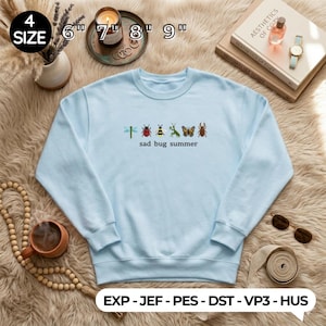 May include: A light blue sweatshirt with a crew neck and long sleeves. The front features embroidered insects and the text "sad bug summer". The sizes are 6", 7", 8", and 9".