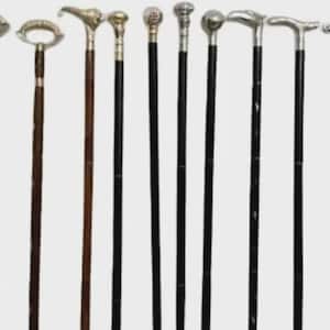 May include: A collection of nine walking sticks arranged in a row. The sticks feature various decorative silver-toned metal handles in shapes including loops, animal heads, and spheres, attached to either dark brown or black wooden shafts.