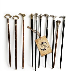 Op de afbeelding: Een collectie van negen wandelstokken met donkerhouten of zwarte schachten en diverse metalen handgrepen, waaronder dierlijke en geometrische vormen. Een beige label toont ALFA NAUTICAL TRUST & QUALITY en een messing plaatje toont ALFA NAUTICAL EST. 1974.