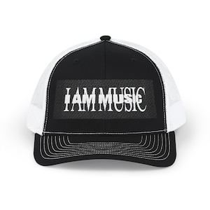 Peut inclure: Casquette de camionneur noire et blanche avec le texte "I AM MUSIC" en lettres blanches. La casquette présente un panneau avant noir, un dos en filet blanc et une visière incurvée avec des coutures blanches. Un accessoire élégant pour les mélomanes.