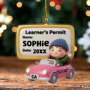 May include: A rectangular acrylic ornament featuring a Learner's Permit sign with the name SOPHIE and date 20XX. Below, a 3D-style cartoon character in a blue beanie drives a pink convertible car with CA license plate and text LOOK OUT WORLD HERE I COME.