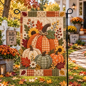 May include: A rectangular garden flag featuring a quilted design of three pumpkins in orange, cream, and green. The pumpkins are surrounded by sunflowers, autumn leaves, and berries on a cream background with a patchwork border of plaid and floral patterns.