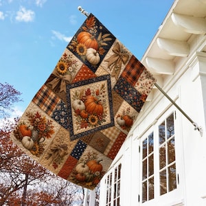 May include: A rectangular outdoor flag featuring a quilted patchwork design with autumn themes. The pattern includes orange pumpkins, sunflowers, brown bows, and plaid fabric sections in shades of orange, brown, navy blue, and cream colors.