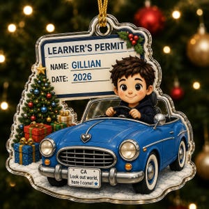 May include: A clear acrylic Christmas ornament featuring a cartoon character driving a blue convertible car. The design includes a sign labeled LEARNER'S PERMIT with the name GILLIAN and date 2026, a decorated Christmas tree, and a license plate reading CA Look out world, here I come!