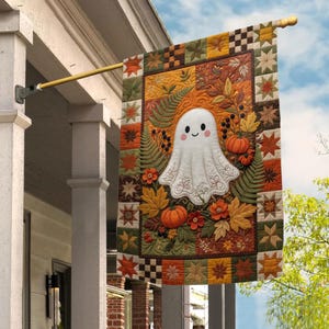 May include: A rectangular garden flag featuring a quilted design with a central white ghost character surrounded by orange pumpkins, green fern leaves, and autumn foliage. The border consists of a patchwork pattern of stars and checkered squares.