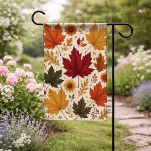 May include: A rectangular garden flag featuring a repeating pattern of autumn maple leaves in shades of red, orange, yellow, and dark green against a cream background, interspersed with small brown floral accents and berry sprigs.