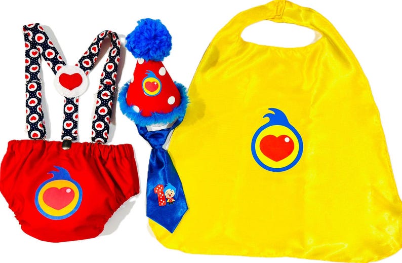 May include: A colorful baby outfit set featuring a red diaper cover, suspenders, a party hat, a blue tie, and a yellow cape. The suspenders have a white heart design. The set is designed with a heart logo.