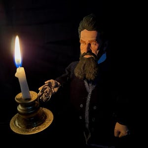 May include: A figure of a man with a long beard, holding a candle in a brass holder and a pocket watch. The candle flame is lit, casting a warm glow on the man's face and the brass. The man is wearing a dark coat.