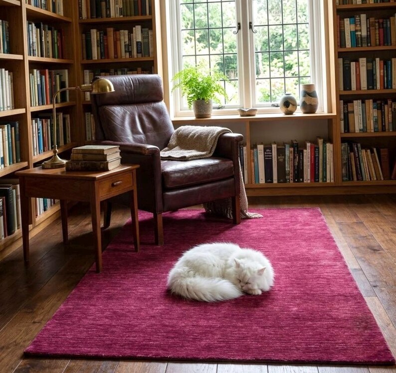 Puede incluir: Una alfombra rectangular de color magenta con una superficie tejida y texturizada. La alfombra est&aacute; colocada sobre un suelo de madera oscura y presenta un color rosa intenso y s&oacute;lido en toda su superficie, creando un contraste vibrante.