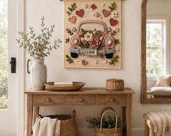 Puede incluir: Un tapiz de ganchillo rectangular que muestra un coche vintage rosa lleno de flores y corazones variados. El coche tiene una matrícula que dice LOVE. La pieza está elaborada con hilo texturizado en tonos rosa, verde y crema.