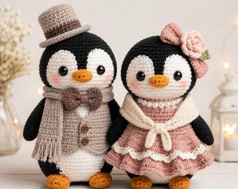 Puede incluir: Dos muñecos de pingüino tejidos a ganchillo. El pingüino de la izquierda lleva un sombrero de copa beige, una bufanda a juego y un chaleco con dos botones. El de la derecha lleva un vestido rosa con encaje blanco, un chal blanco y un collar de perlas.