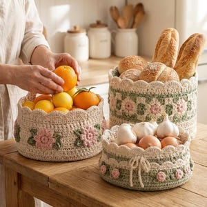 Puede incluir: Tres cestas redondas de ganchillo con bordes festoneados y motivos florales. Una cesta contiene naranjas y limones, otra barras de pan y la tercera bulbos de ajo y cebollas. Las cestas están hechas con hilo de color crema, verde salvia y rosa.