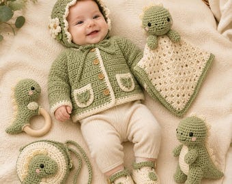 Puede incluir: Un bebé con una chaqueta de ganchillo verde salvia con botones de madera, un gorro a juego con una flor y pantalones color crema. Incluye un sonajero de ganchillo de dinosaurio, una manta de seguridad, un bolso redondo y patucos.