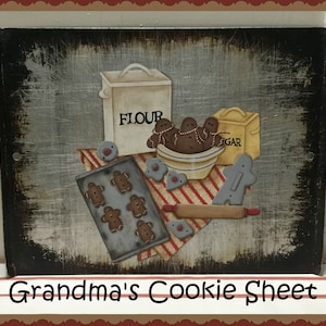 Puede incluir: Un letrero de madera desgastado con una escena pintada de galletas de jengibre, un rodillo, una bandeja para hornear, un tazón de masa y recipientes etiquetados como "Harina" y "Azúcar". El letrero dice "Grandma's Cookie Sheet".