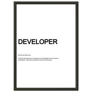 Peut inclure: Une affiche encadrée avec le mot DEVELOPER en caractères noirs gras sur fond blanc. Sous le mot se trouve la prononciation phonétique [dih-rel-uh-per] nom et la définition : A wizard who speaks to machines in a language humans cannot understand. They solve problems that do not exist yet.