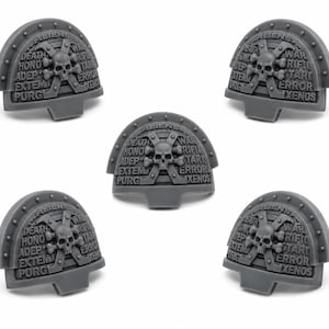 May include: Five gray plastic shoulder pads with a skull and crossbones emblem. Each pad has the words "ALIENS", "DEATH", "HONO", "ADEP", "EXTEM", "PURG", "WAR", "RIFIL", "TART", "ERROR", and "XENOS" inscribed. The pads are designed for miniature wargaming.
