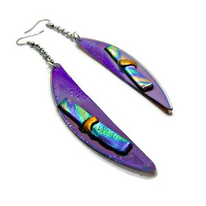 May include: A pair of dangle earrings with a purple, iridescent, leaf-shaped design. Each earring features a rectangular, multi-colored glass accent with a gold-colored band. The earrings have silver-colored chain and hook closures.
