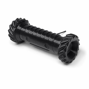 May include: A black cylindrical object with a ribbed central body and two large, thick-treaded wheels at each end. The central section features a series of horizontal grooves and two circular indentations, with a thin, straight antenna protruding.