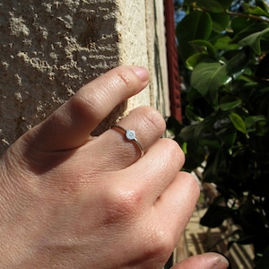 Pu&ograve; includere: Un anello d'argento con un piccolo design a forma di faccina sorridente. L'anello &egrave; indossato al dito di una persona.