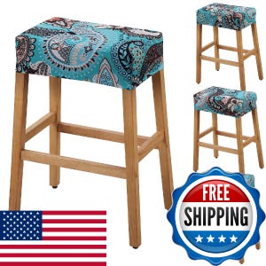 May include: A rectangular stool with four light-coloured wooden legs and a padded seat cover featuring a vibrant turquoise, black, and white paisley pattern. The stool has a simple frame with horizontal support bars connecting the four legs.
