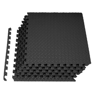 Könnte beinhalten: Ein Stapel quadratischer schwarzer Schaumstoff-Bodenfliesen mit ineinandergreifendem Puzzle-Kanten-Design. Jede Fliese weist eine strukturierte Riffelblech-Oberfläche auf. Ein einzelner, abgetrennter Kantenstreifen befindet sich links.
