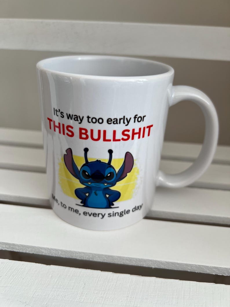 Peut inclure: Un mug en c&eacute;ramique blanche avec une illustration du personnage bleu Stitch de Lilo et Stitch. Le texte indique : It's way too early for THIS BULLSHIT. Sous le personnage, le texte ajoute : Me, to me, every single day. Le mug a une anse.