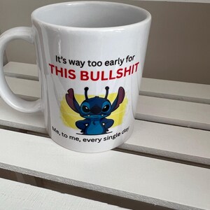 Peut inclure: Un mug en c&eacute;ramique blanche orn&eacute; d'un personnage de dessin anim&eacute; bleu aux grandes oreilles et d'une inscription : It's way too early for THIS BULLSHIT. Sous le personnage, le texte ajoute : Me, to me, every single day.