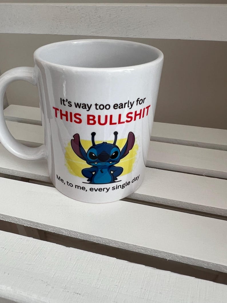 Peut inclure: Un mug en c&eacute;ramique blanche orn&eacute; d'un personnage de dessin anim&eacute; bleu aux grandes oreilles et d'une inscription : It's way too early for THIS BULLSHIT. Sous le personnage, le texte ajoute : Me, to me, every single day.