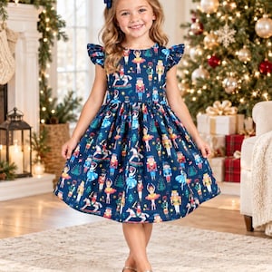 May include: A navy blue knee-length dress featuring a repeating print of nutcrackers, ballerinas, and Christmas trees. The dress has short flutter sleeves, a round neckline, and a gathered waistline that flares into a full skirt.