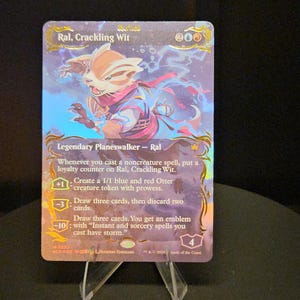 Puede incluir: Una carta coleccionable holográfica de Magic: The Gathering titulada Ral, Crackling Wit, con tonos azules y rojos y la ilustración de un personaje con bufanda. La carta muestra texto que detalla las habilidades, costes y un valor de lealtad de 4.