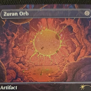 May include: A Zuran Orb Magic: The Gathering trading card featuring a glowing yellow orb in a dark, cavernous landscape. The card text reads: Sacrifice a land: You gain 2 life. Each probe surveys the void, seeking life only to consume it.