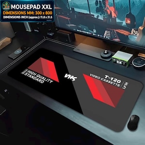 Può includere: Tappetino per mouse XXL nero e grigio con un design a videocassetta VHS. Il tappetino misura circa 30 x 80 cm e presenta il testo "HIGH QUALITY STANDARD" e "T-120 VIDEO CASSETTE".