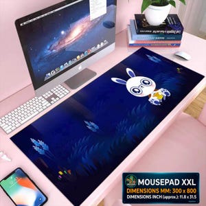 Puede incluir: Alfombrilla de ratón XXL rectangular con un fondo azul oscuro y un diseño de conejo de dibujos animados. La alfombrilla mide aproximadamente 300 x 800 mm. El diseño incluye un personaje de conejo con ojos grandes y una pequeña bolsa amarilla. En un escritorio rosa.