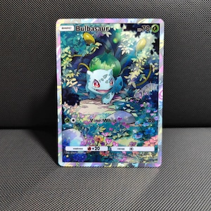 May include: A holographic Bulbasaur trading card featuring the character in a lush, colorful forest setting with flowers and foliage. The card displays the text Bulbasaur, HP 70, Vine Whip, 40, and includes weakness and retreat information.