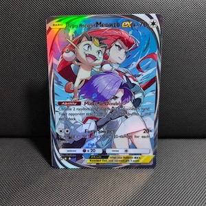 May include: A Team Rocket's Meowth ex trading card featuring illustrations of Meowth, Jessie, and James. The card displays the Ability Make It Double and the Fury Swipes attack. It has a holographic finish with blue, red, and purple accents.