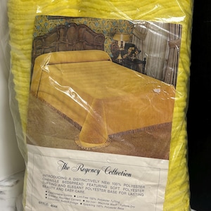 May include: A bright yellow chenille bedspread packaged in a clear plastic bag. The packaging features a product image of a bed with the bedspread, the text The Regency Collection, and details stating it is 100% polyester with bullion fringe.