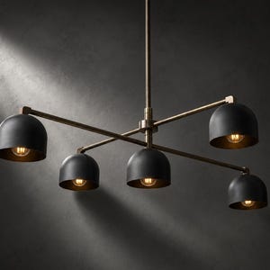 May include: A five-light chandelier featuring a central vertical rod with two horizontal arms extending outwards. Each arm holds matte black dome-shaped shades with warm glowing light bulbs inside. The fixture is finished in a dark bronze metal.