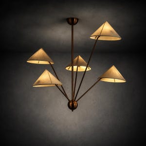 May include: A ceiling chandelier featuring a central dark bronze rod and a spherical base with five radiating arms. Each arm supports a conical, off-white fabric lampshade that emits a warm, soft glow, creating a multi-directional lighting effect.