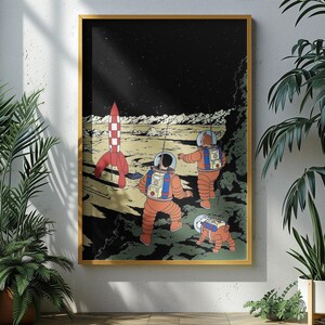 May include: A framed print featuring a retro-style illustration of astronauts exploring a lunar landscape. The artwork depicts two astronauts in orange suits, a red and white rocket, and a space dog. The background is a starry night sky.