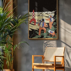 May include: A framed art print featuring a retro-style illustration of astronauts exploring a lunar landscape. The artwork depicts a red and white rocket, three astronauts in orange suits, and a small robot on the moon's surface. The background is a starry night sky.