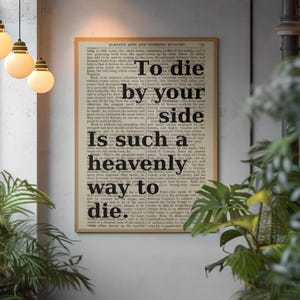 Puede incluir: Un estampado enmarcado con el texto "To die by your side is such a heavenly way to die" en negro. El texto está sobre un fondo de página de libro antiguo, enmarcado en un marco marrón claro. El estampado se muestra en una pared gris.