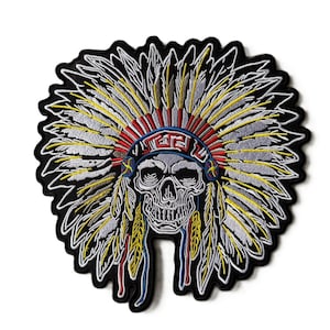 May include: An embroidered patch featuring a human skull wearing a large feathered headdress. The skull is white with black shading, and the headdress consists of white, yellow, and red feathers with a blue and red patterned headband border.