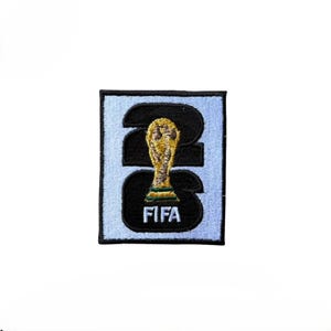 May include: A rectangular embroidered patch featuring a light blue background with a large black number 26. Centered over the numbers is a gold and green FIFA trophy icon, with the white text FIFA positioned directly below the trophy graphic.
