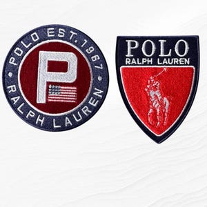 May include: Two embroidered patches. The circular patch is navy blue with white text reading POLO EST. 1967 RALPH LAUREN, featuring a red center with a white letter P and a small American flag. The shield-shaped patch is navy blue with a red center.