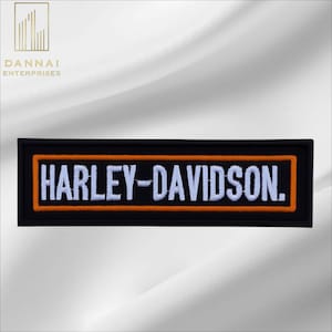 May include: A rectangular embroidered patch featuring a black background with a bold orange border. The text HARLEY-DAVIDSON is stitched in white capital letters across the center of the patch, creating a clear and high-contrast design.