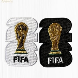 May include: Two embroidered patches, one white and one black, each featuring the number "23" with a gold trophy and the word "FIFA" in white. The patches are likely for apparel or accessories.